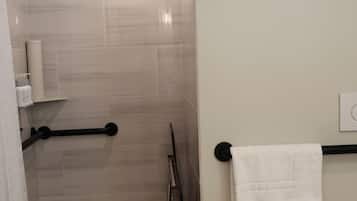 Une salle de bain moderne équipée d’une douche, de toilettes et d’un porte-serviettes.