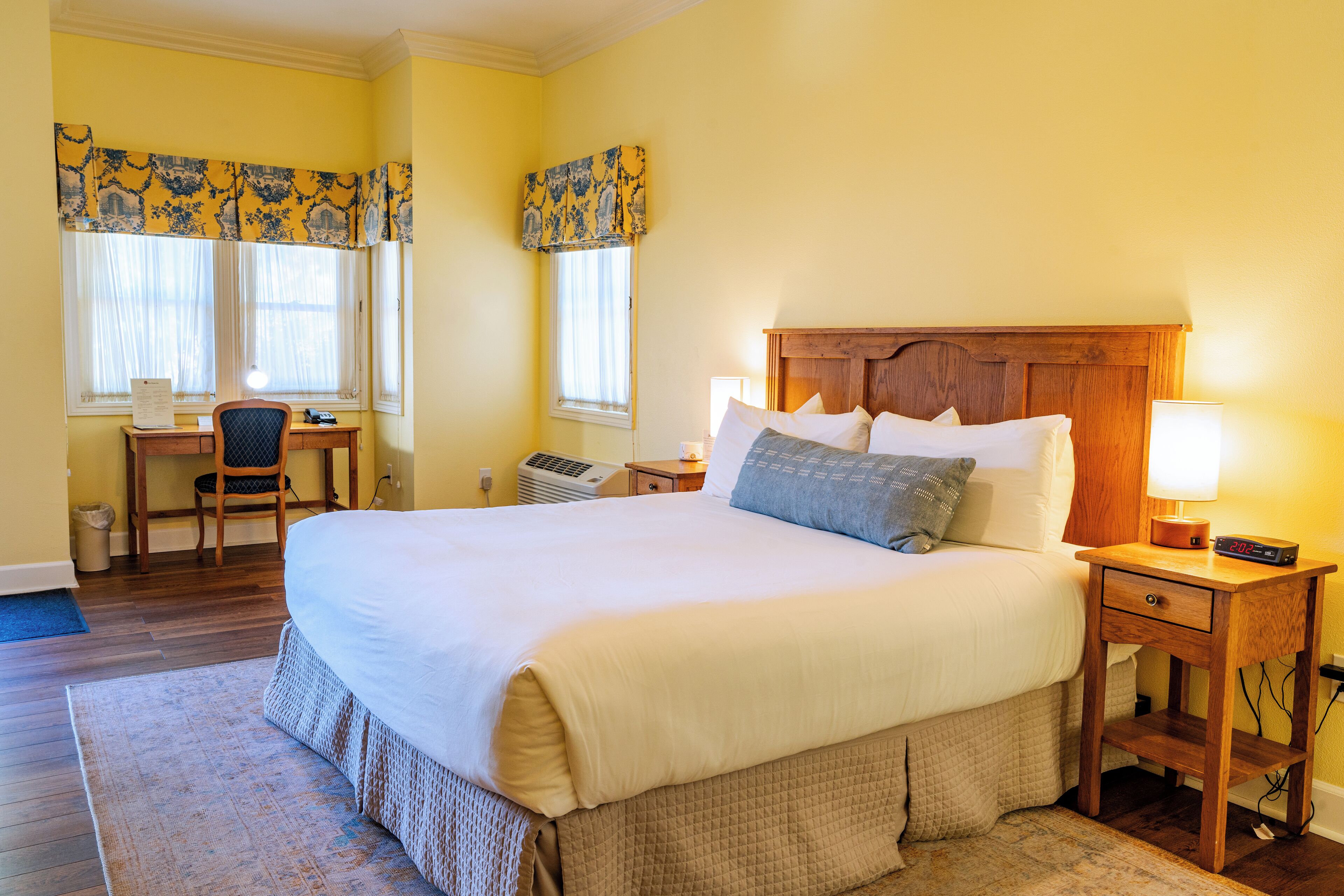 A neatly arranged bedroom with a large bed, bedside tables, a chair, and a desk.
