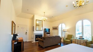 A spacious room with a large bed, a fireplace, a sofa, and a television. - Elm House Inn (Napa)