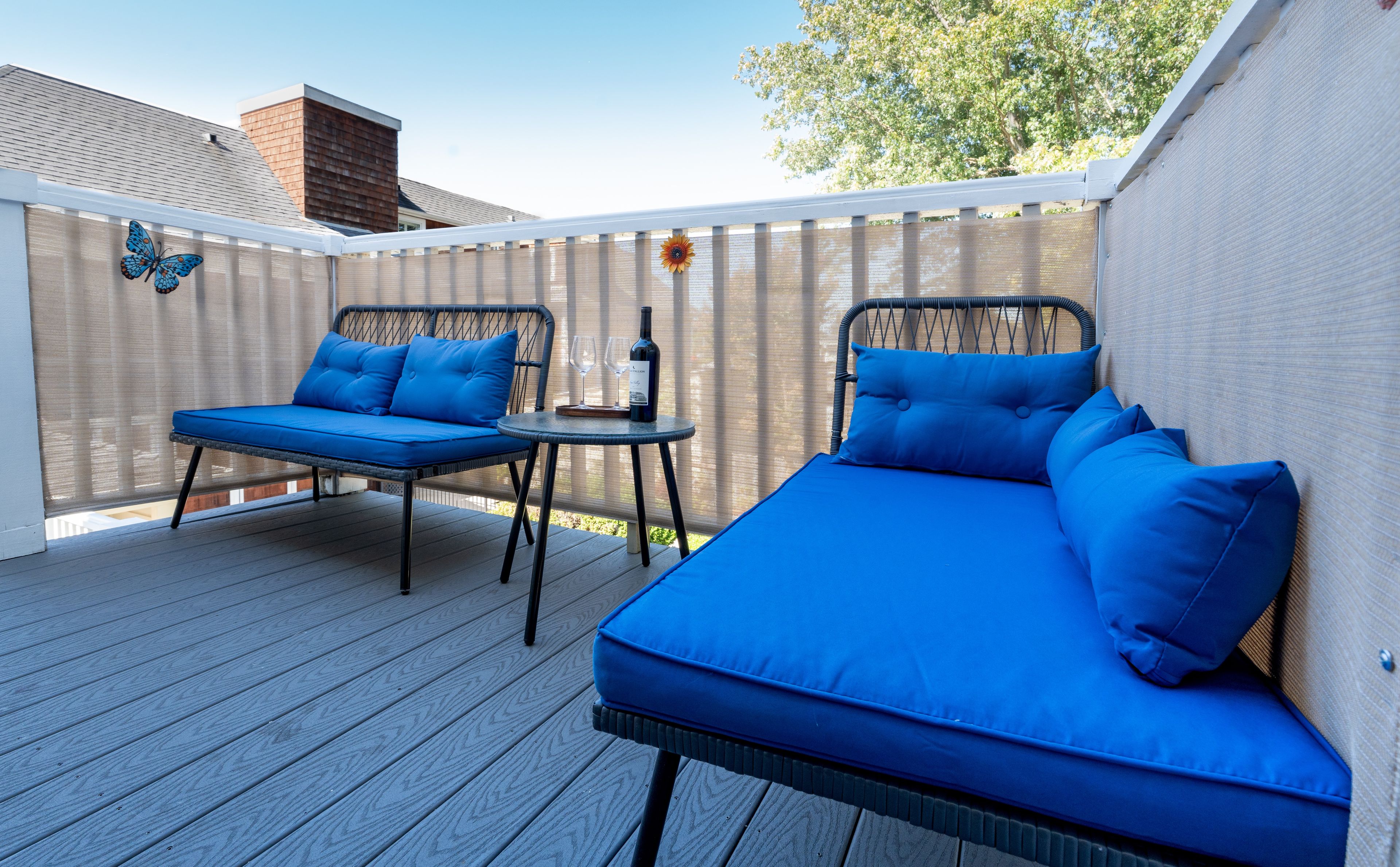 Een gemeenschappelijk terras met twee zithoekjes met blauwe kussens en een kleine tafel.