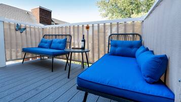 Een gemeenschappelijk terras met twee zithoekjes met blauwe kussens en een kleine tafel.