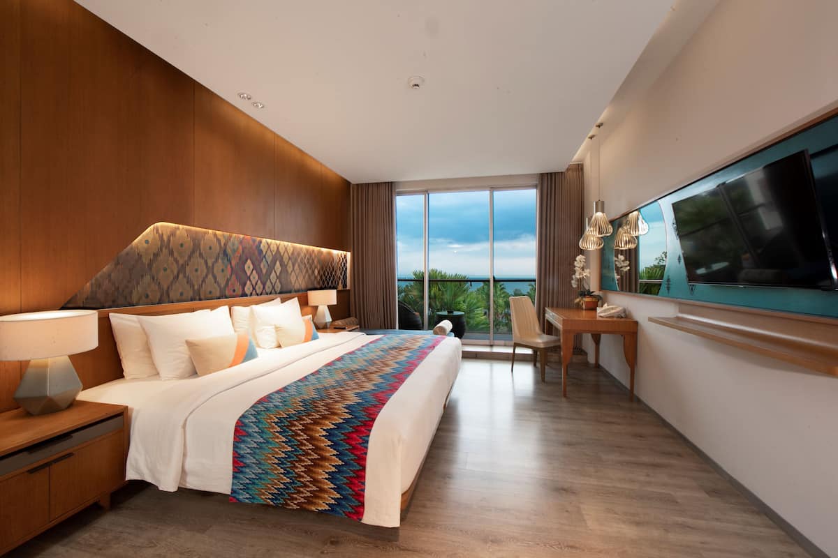A modern hotel room with a large bed, a desk, and a TV.