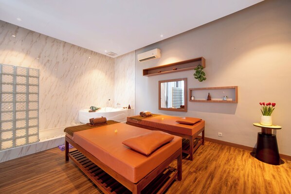 Et moderne spa-rum med to massagestole, et badekar og et lille bord med en vase blomster.