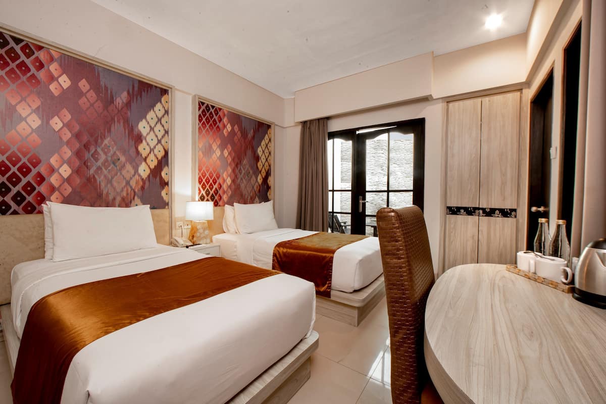 A hotel room with two beds, a wooden dining table, a chair, and a large window.
