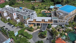 Un hotel moderno con piscina en la azotea, un espacio al aire libre cubierto y un jardín ajardinado.