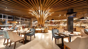 Un restaurante moderno con vigas de madera en el techo, mesas redondas y sillas azules.