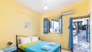 Quarto com cama, mesa de cabeceira e janela com cortinas.