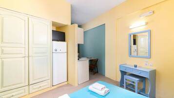 Ein kleines Zimmer mit Bett, Schreibtisch und Kleiderschrank.