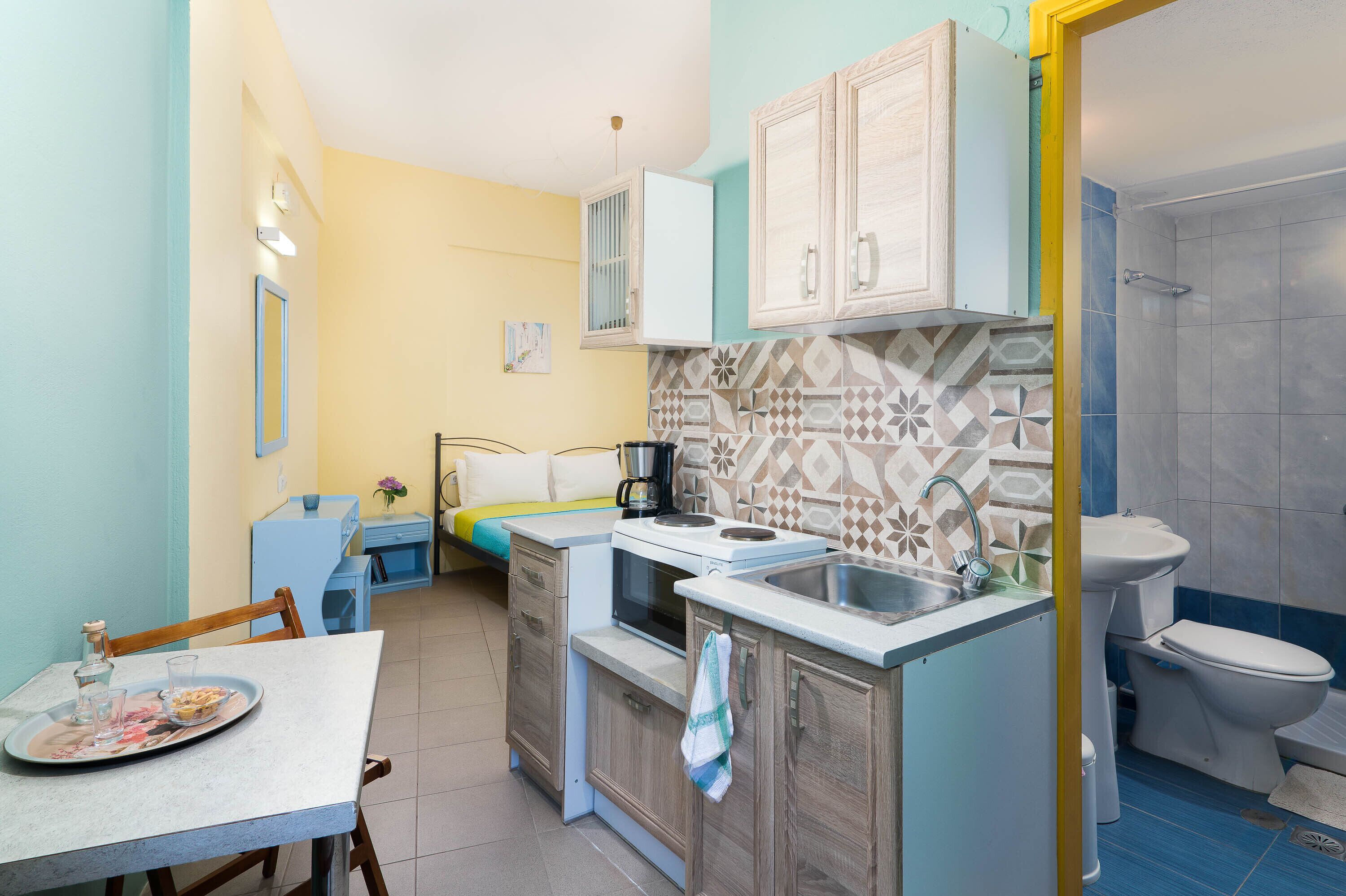 A compact kitchen with a dining table, a microwave, a sink, and a toilet.