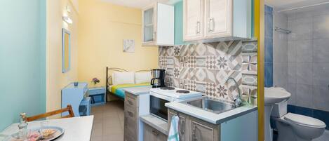 A compact kitchen with a dining table, a microwave, a sink, and a toilet.