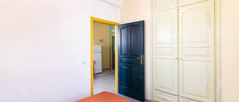 Una habitación con dos camas, un armario y una puerta que da a una cocina.