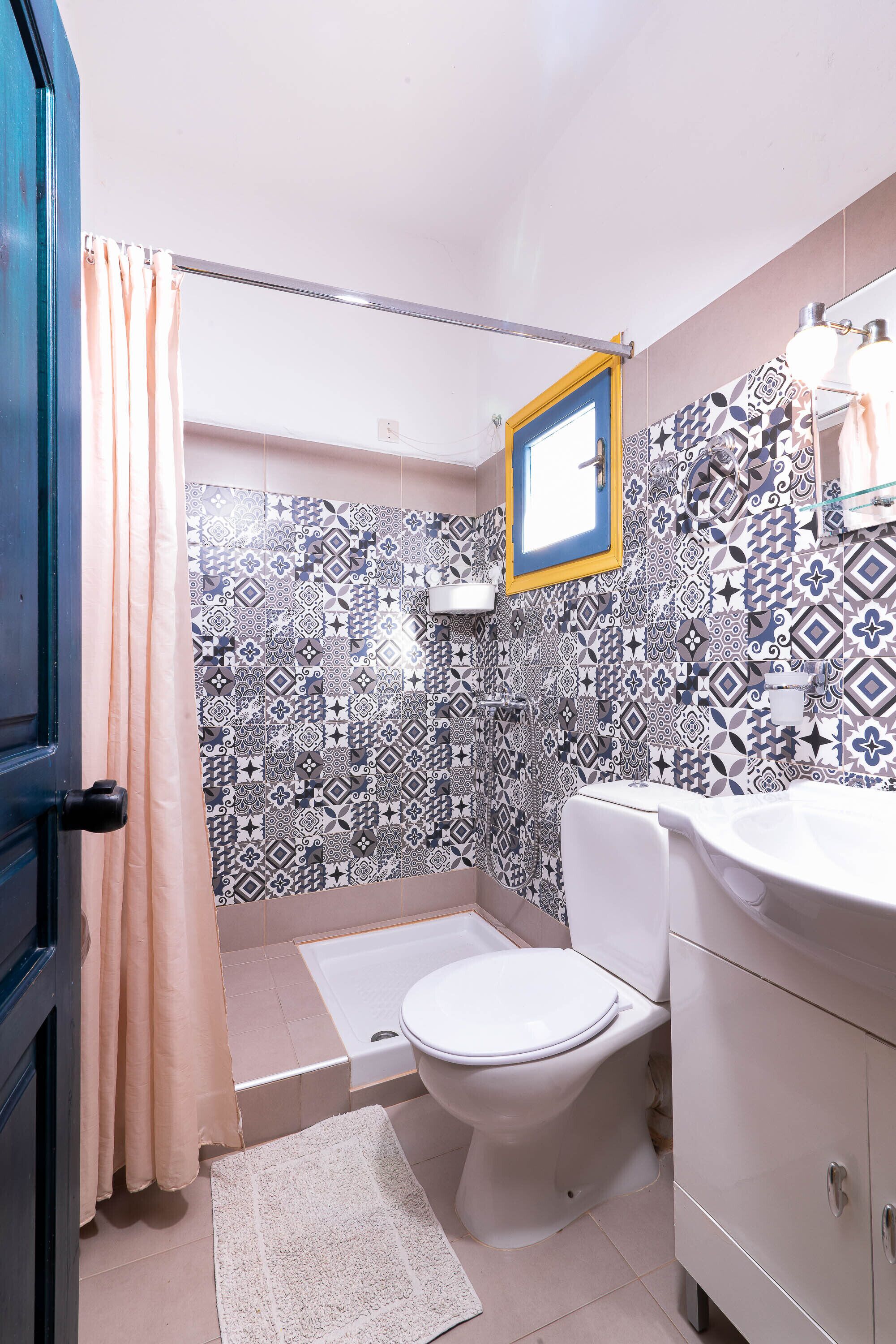 Een badkamer met betegelde vloer, een wit toilet, een wastafel en douchegordijn.