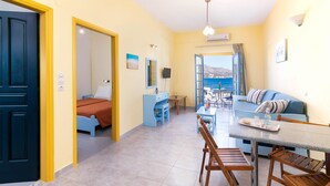 Quarto de hotel com cama, escrivaninha, mesa de jantar e varanda com vista.