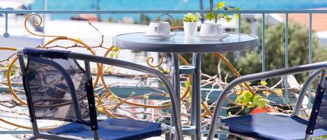 A balcony with a table and chairs, overlooking a body of water.