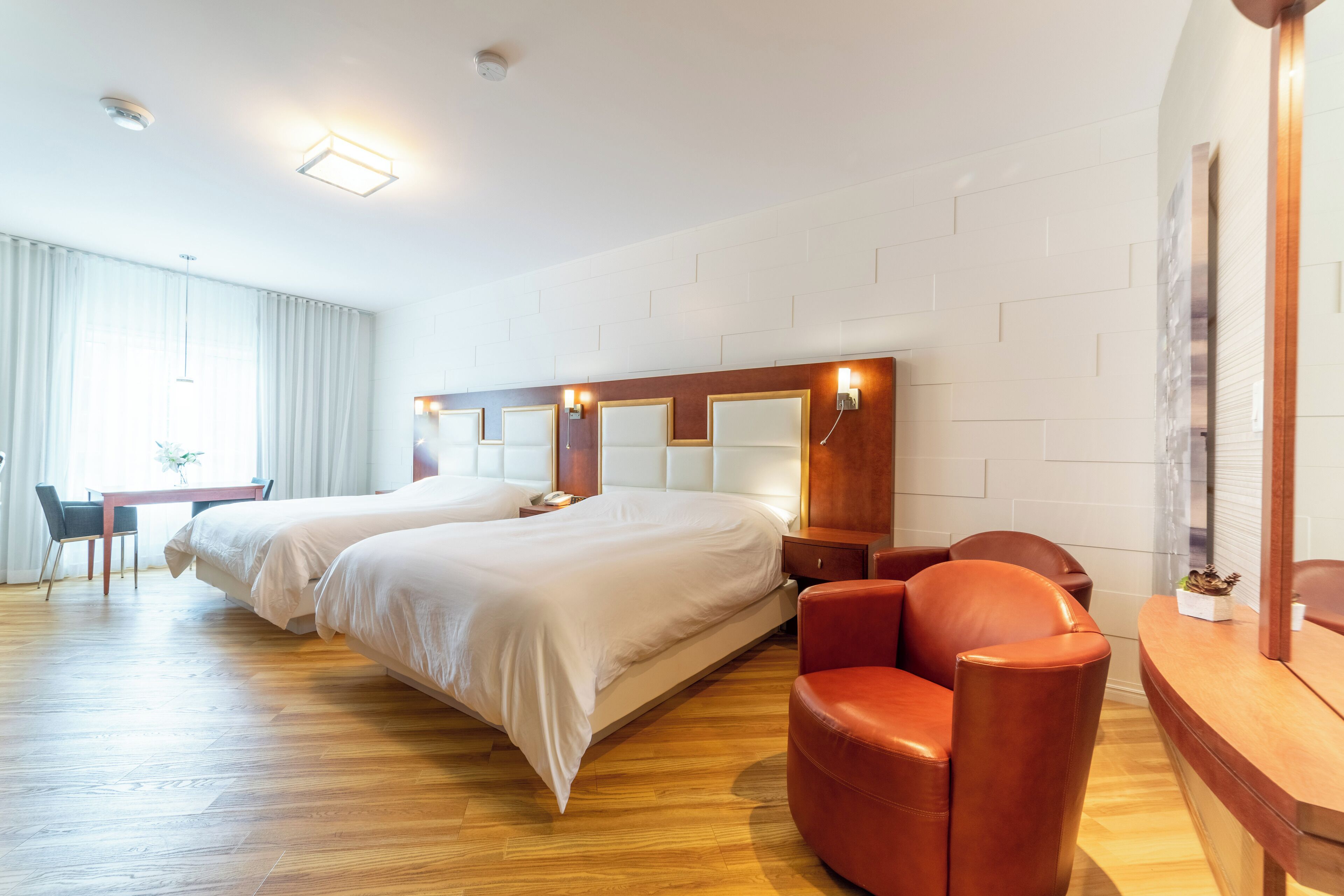 Una habitación de hotel con dos camas, un escritorio, una silla y un espejo grande.