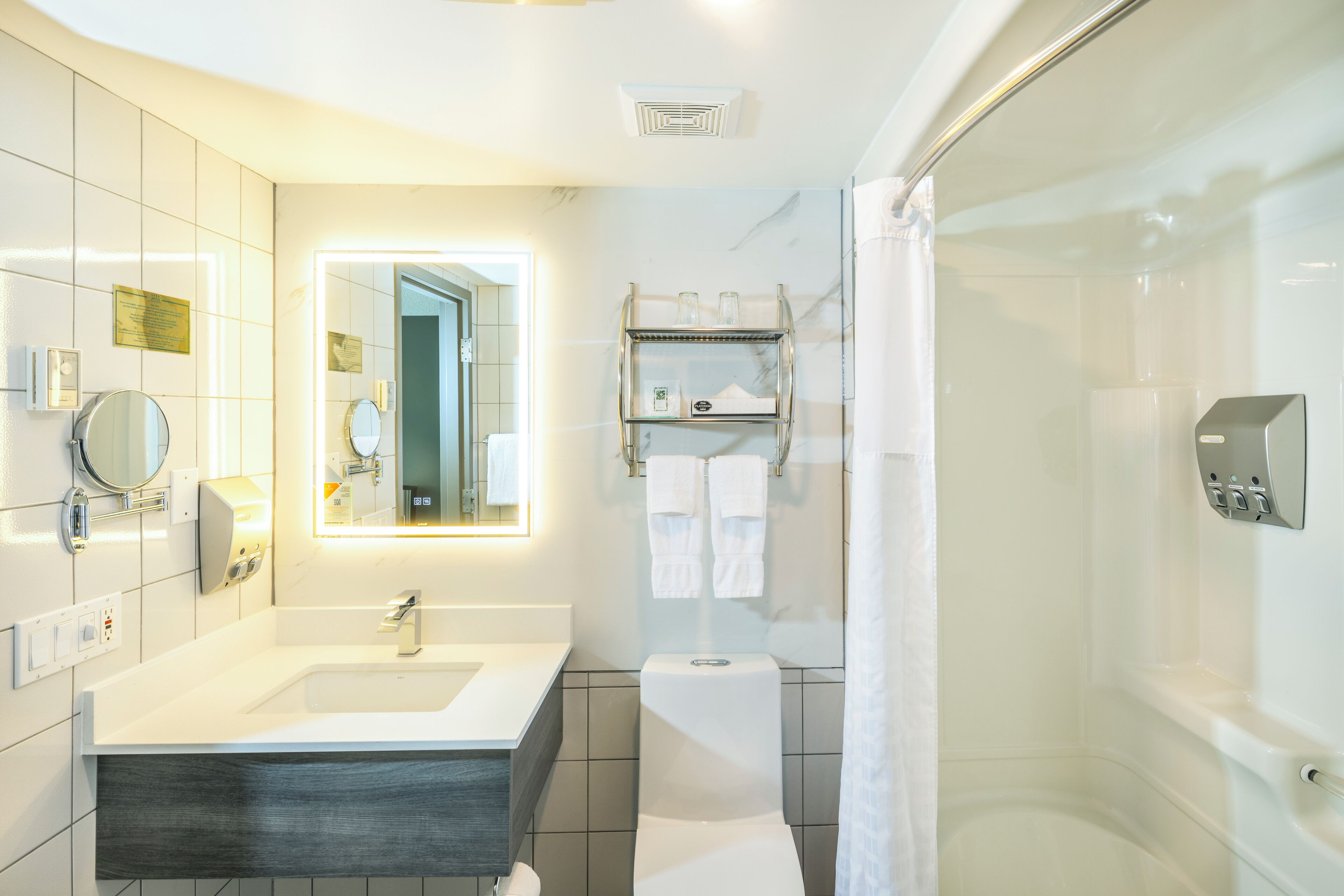 A modern bathroom with a large mirror, a sink, a toilet, and a shower area.