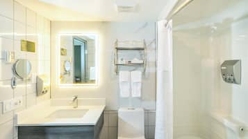 A modern bathroom with a large mirror, a sink, a toilet, and a shower area.