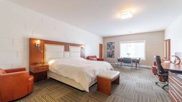 Quarto de hotel com uma cama grande, uma escrivaninha, uma cadeira e um pequeno espaço de estar.