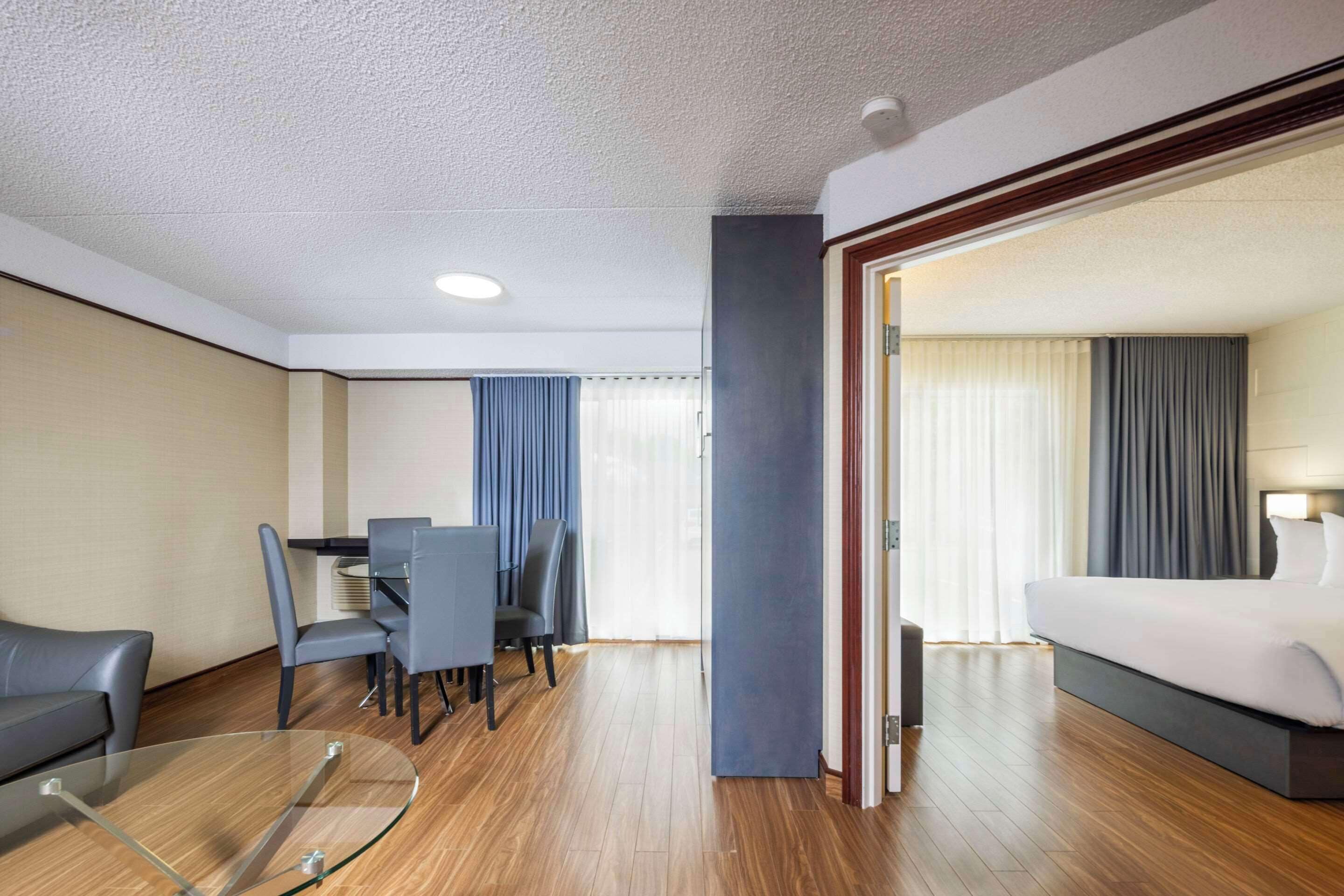 Une chambre d’hôtel comprenant un lit, un bureau avec des chaises, une table en verre et une vue sur l’extérieur par la fenêtre.