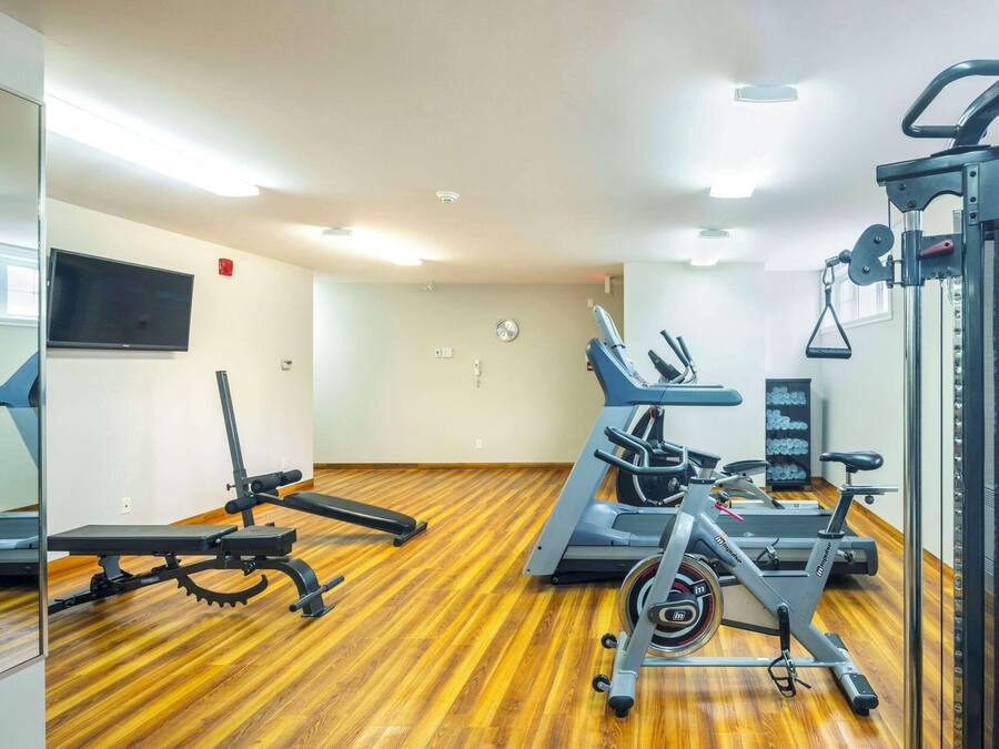 Une salle de sport équipée de tapis de course, de vélos d’appartement et d’appareils de musculation.