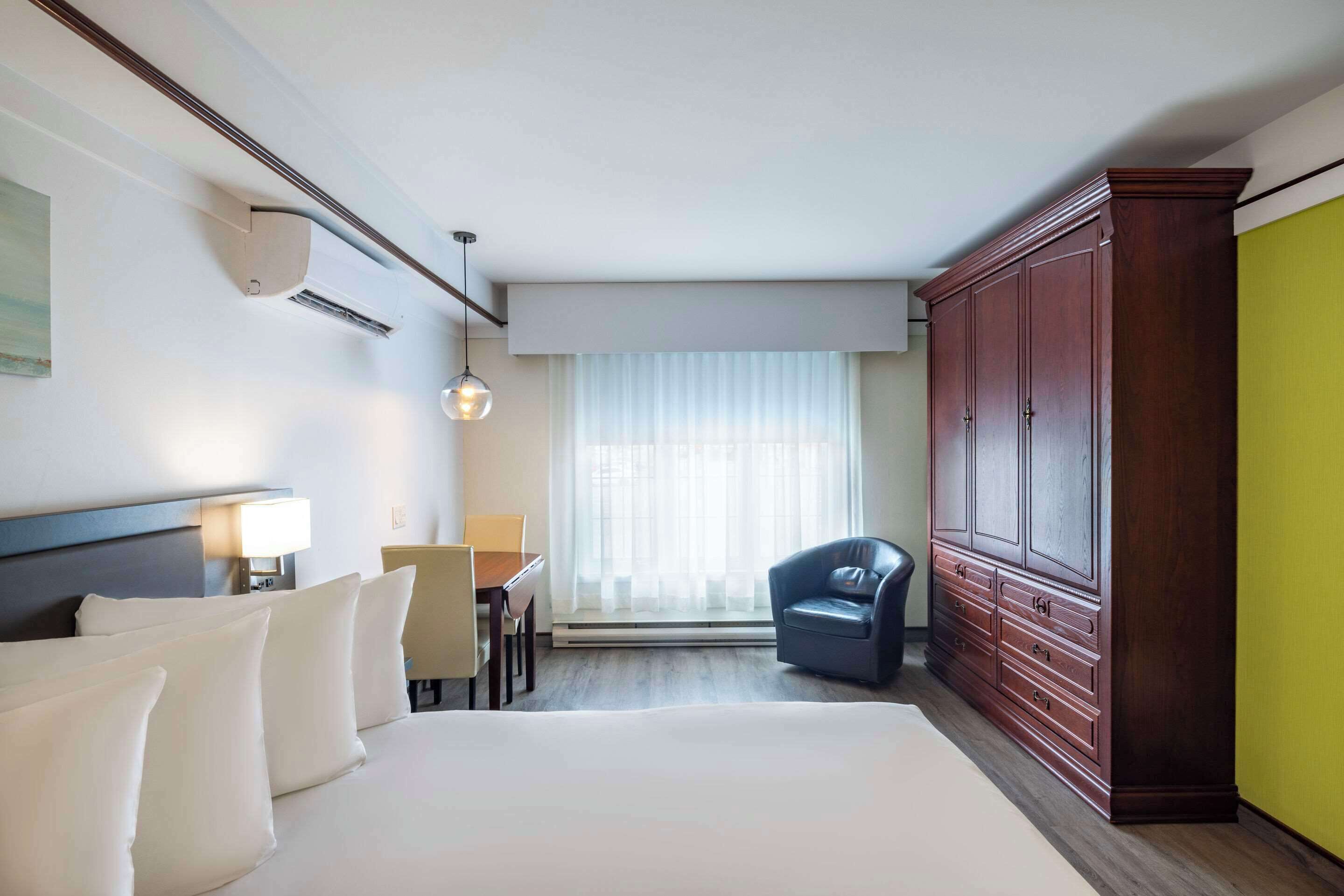 Camera d'albergo con un letto grande, una scrivania con sedia, un armadio e una finestra con tende.