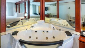 Une salle de bain luxueuse dotée d’une grande baignoire, d’une douche séparée et d’un miroir qui reflète l’ensemble de la pièce.