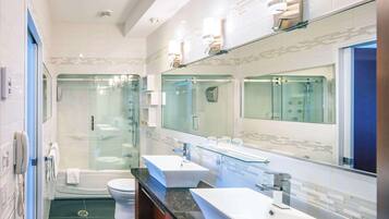 Een moderne badkamer met een douchecabine, een badkuip en een wastafelmeubel met twee wastafels.