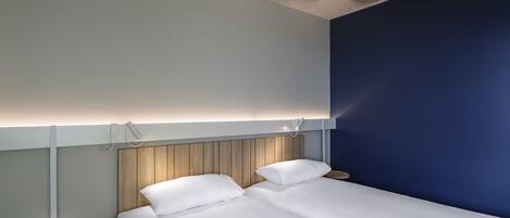 Una habitación de hotel moderna con cama, mesitas de noche y un diseño de techo original.