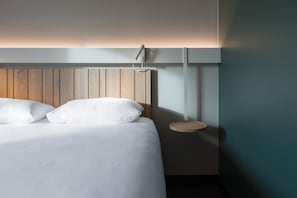 A neatly made bed with white linens and a wooden headboard.