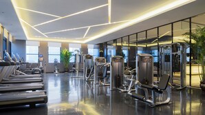 A modern gym with treadmills, weight machines, and a large mirror wall. - Nanjing Wanda Realm Hotel (Nanjing)