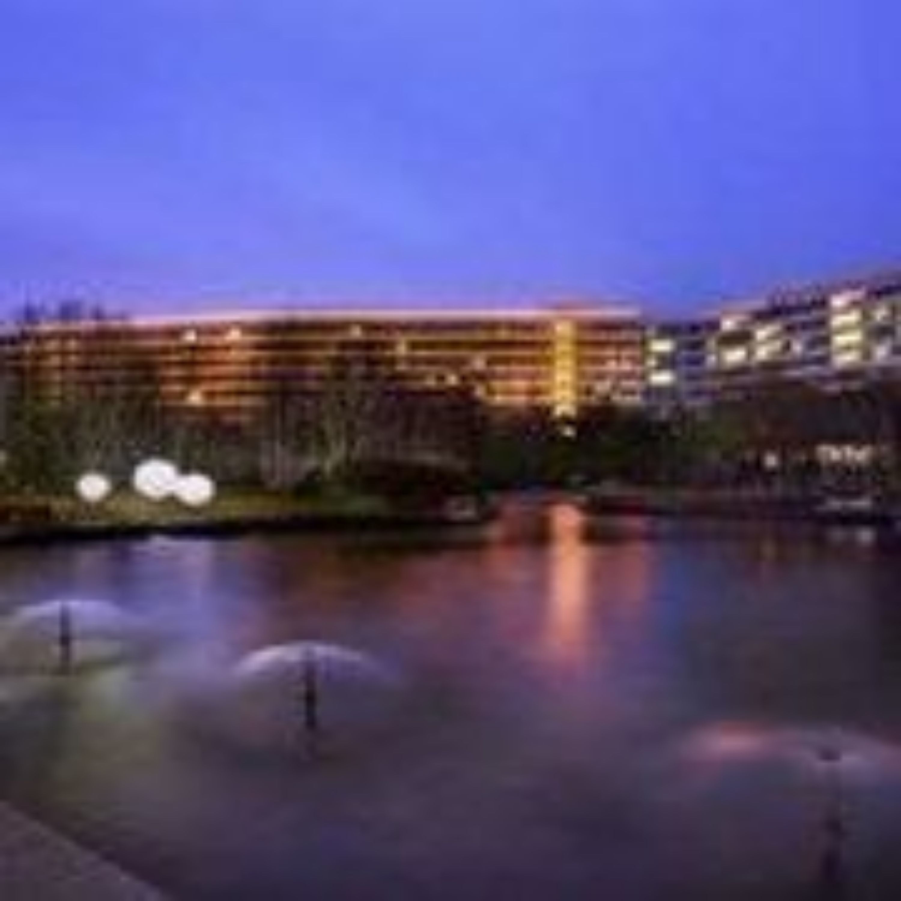 A hotel with a large building, a water feature, and a well-maintained lawn.