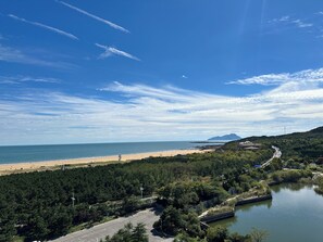 A coastal landscape with a beach, a river, and a forested area. - Wyndham Grand Qingdao (Qingdao)