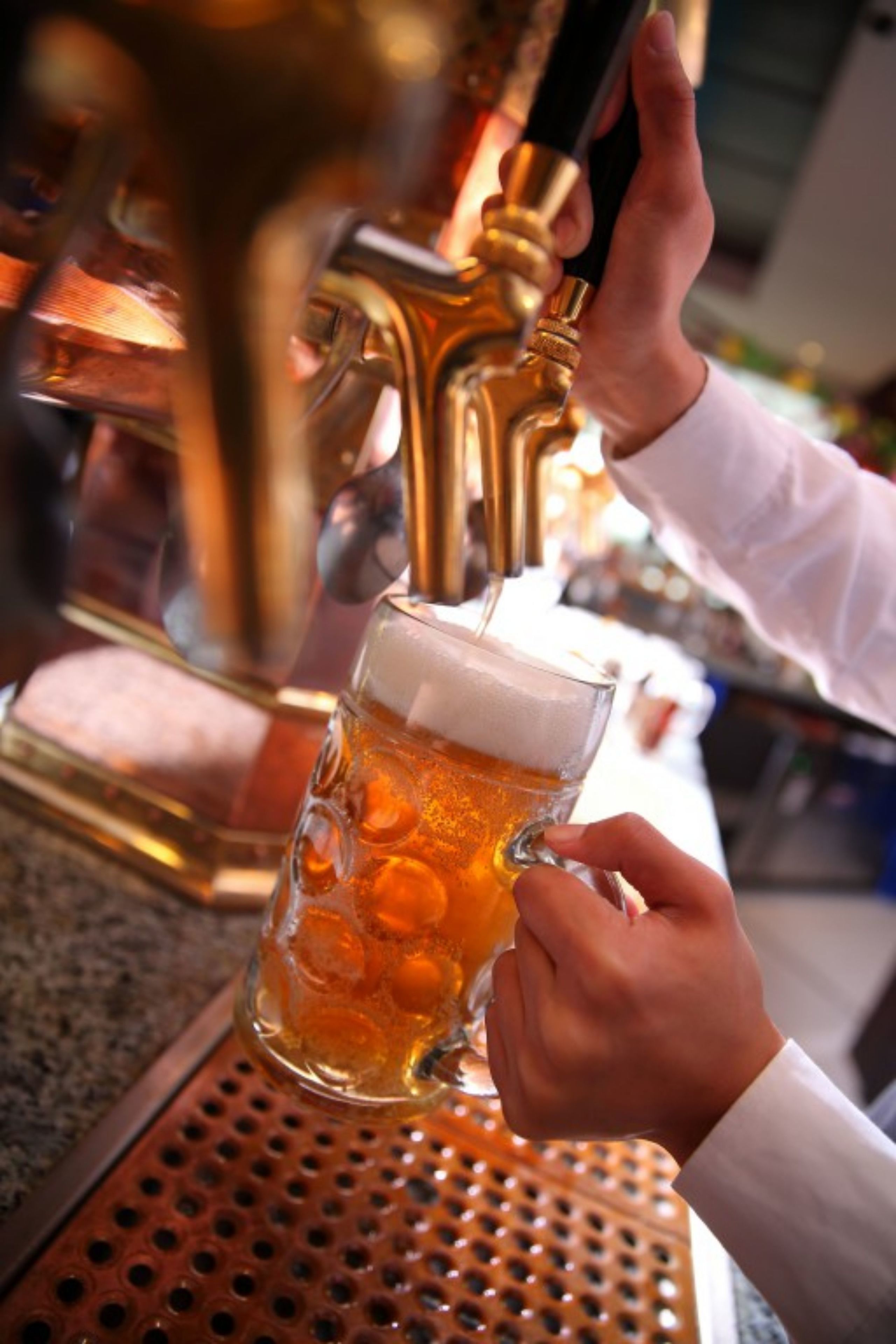 A hand pouring beer into a glass mug.