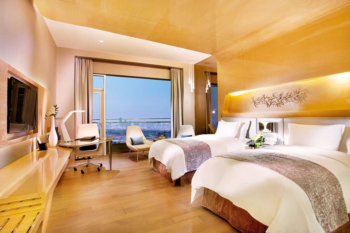 A hotel room with a large bed, a desk, a chair, and a TV.