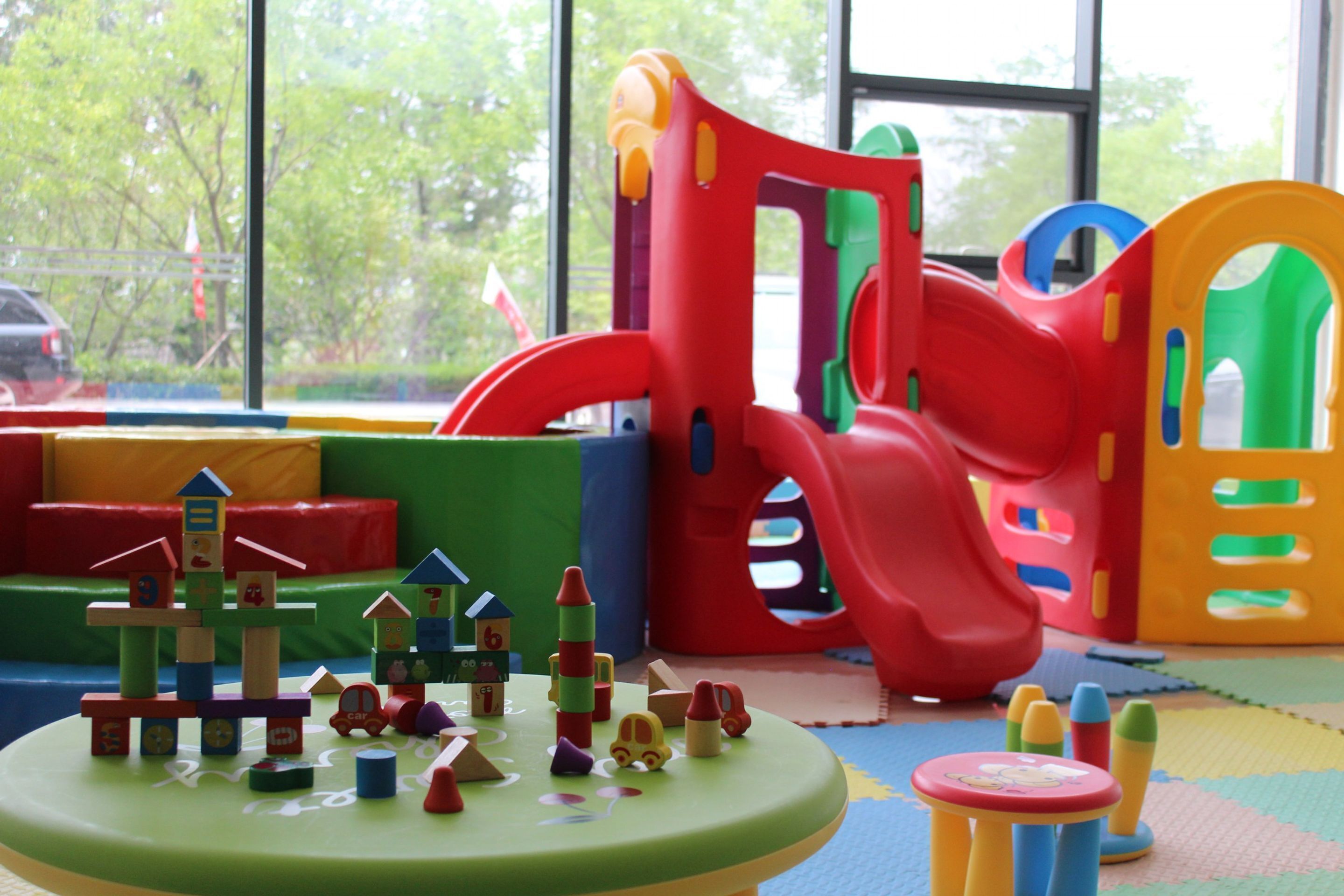 A children's play area with a slide, climbing structures, and a small table with toys.