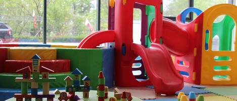 A children's play area with a slide, climbing structures, and a small table with toys.