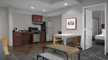 A compact hotel room with a kitchenette, a dining area, and a bed.