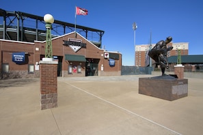 A brick building with a sign reading "Warren Spahn Plaza" and a statue of a baseball player.