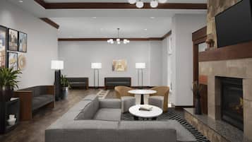A modern lobby with a sectional sofa, a round table, and a fireplace.