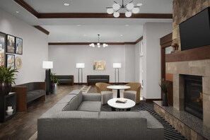 A modern lobby with a sectional sofa, a round table, and a fireplace.