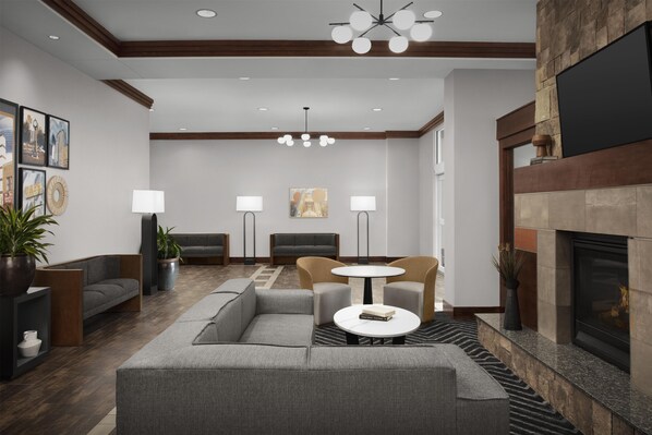 A modern lobby with a sectional sofa, a round table, and a fireplace.
