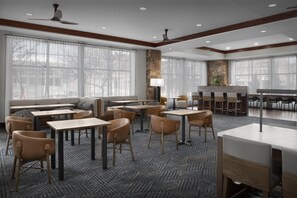 A modern dining area with tables and chairs, large windows, and a stone accent wall.