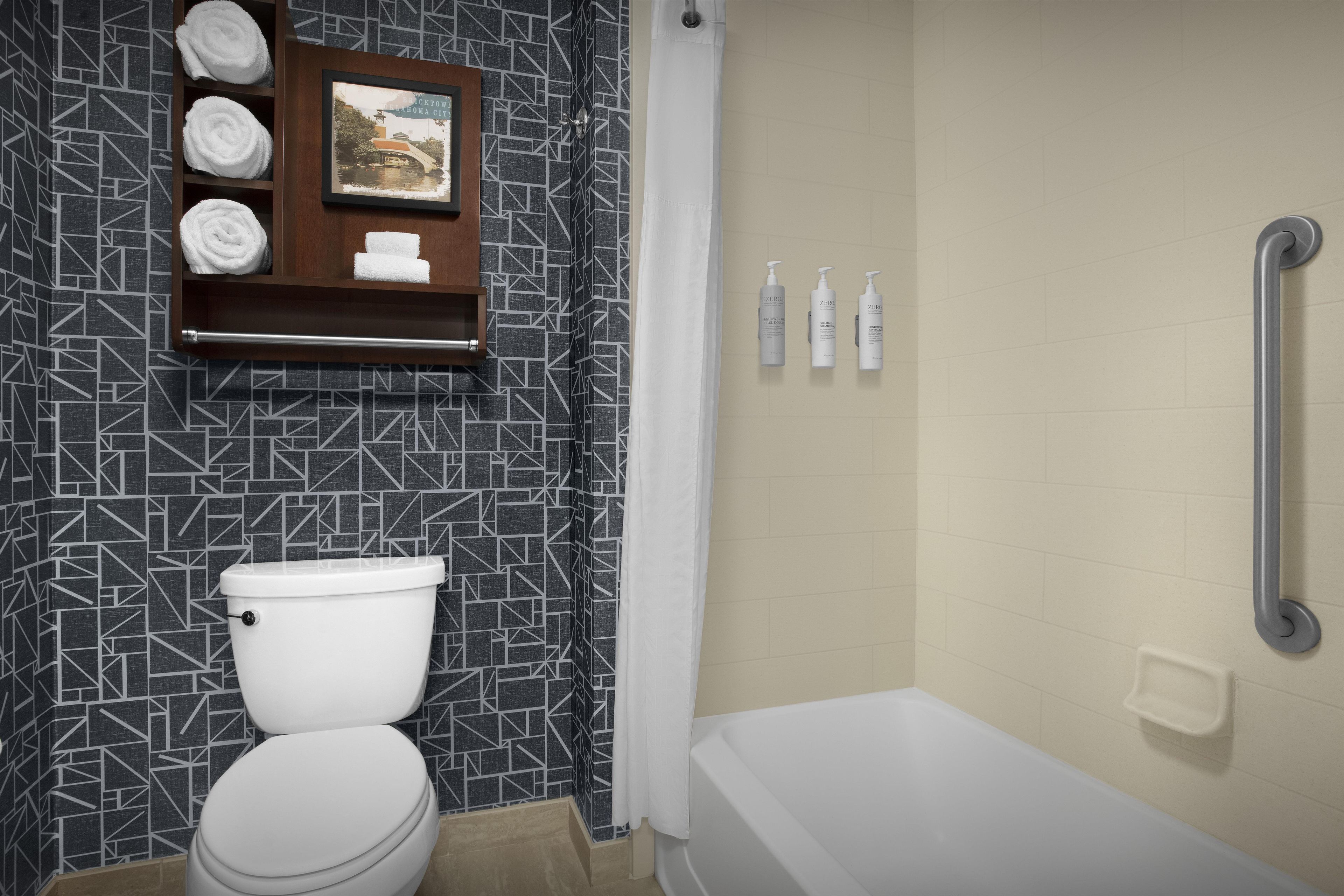 A bathroom with a toilet, a shower area, and a shelf with towels and toiletries.