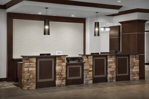 A reception area with a stone counter, a textured wall, and a modern pendant light.