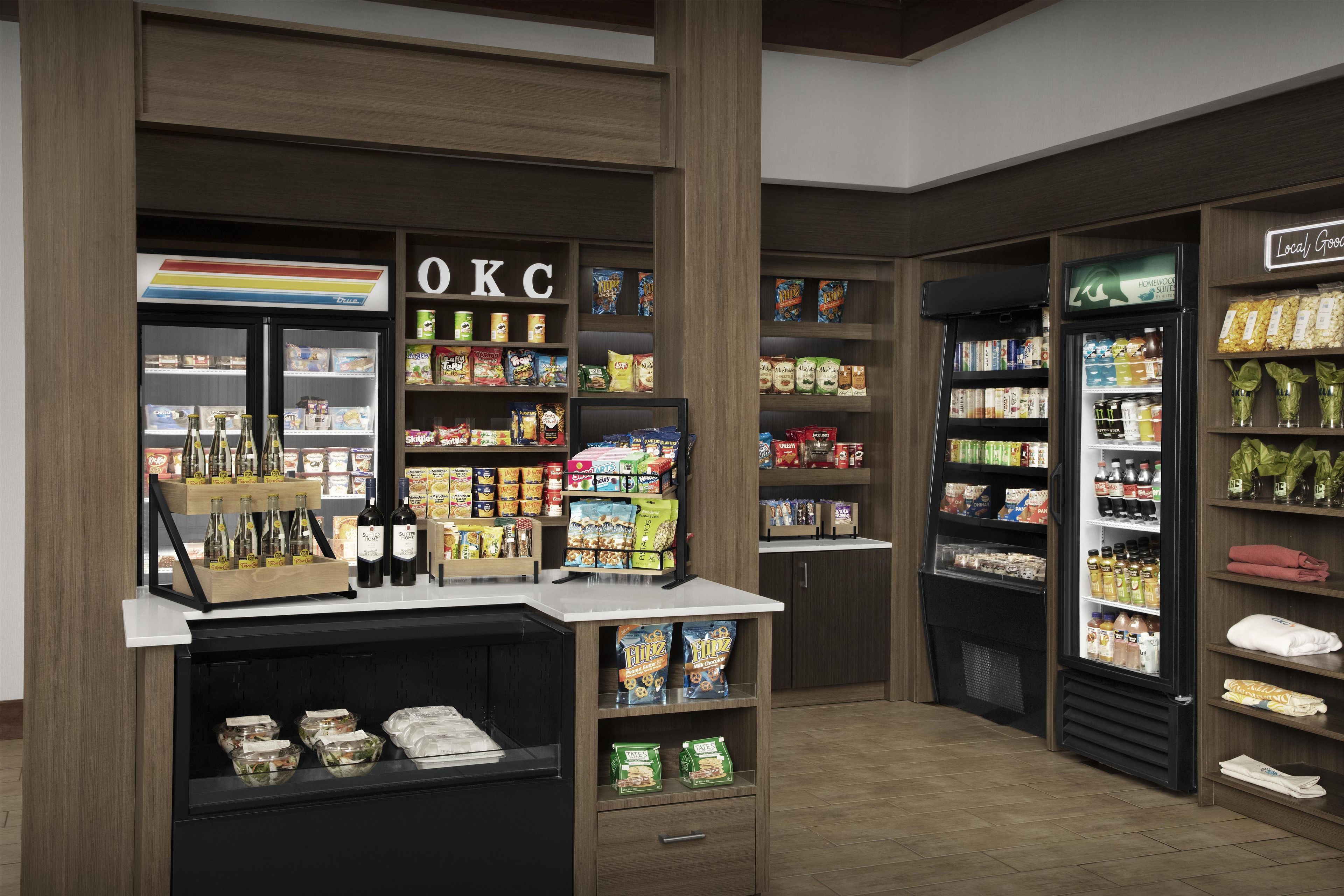 A self-service beverage station with a variety of drinks and snacks, including bottled water, soda, and snacks.