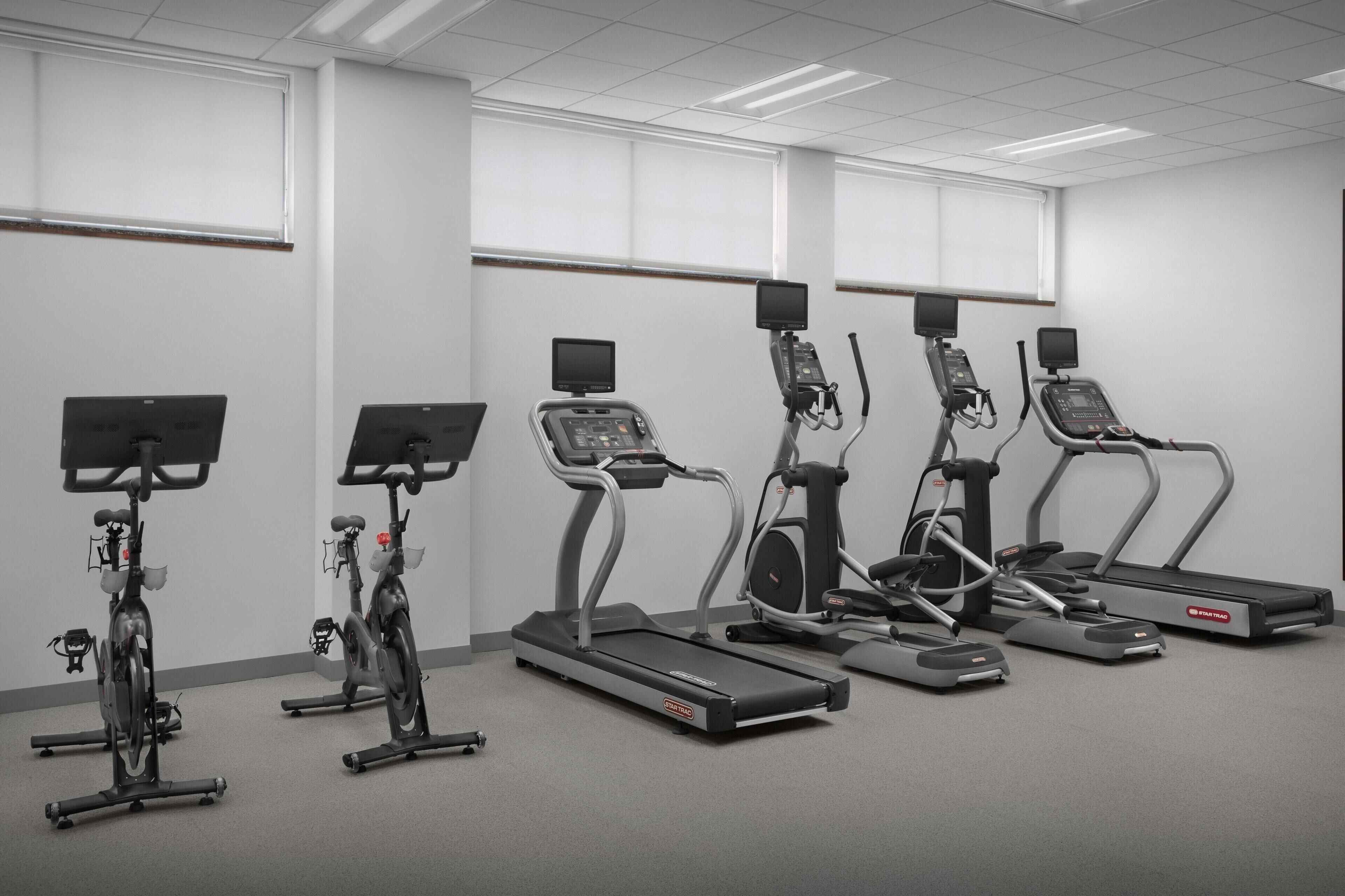 A fitness room with treadmills, ellipticals, and stationary bikes.