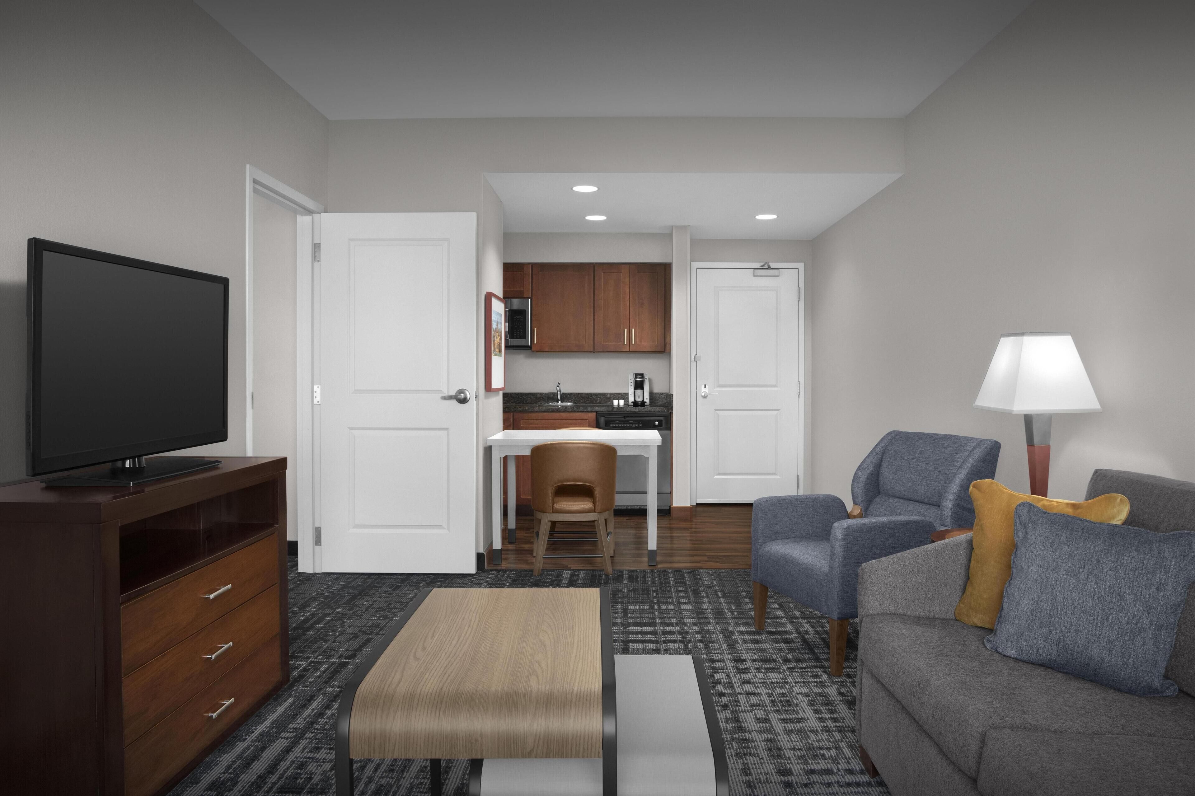 A modern living room with a flat-screen TV, a sofa, a coffee table, and a lamp.
