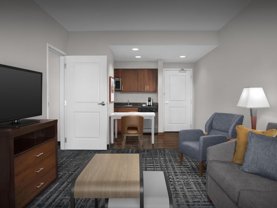 A modern living room with a flat-screen TV, a sofa, a coffee table, and a lamp.