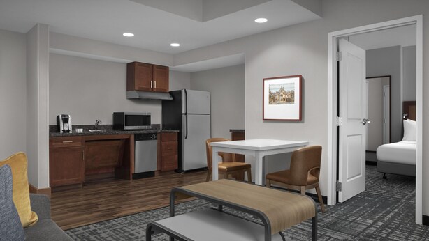 Una habitación de hotel compacta con kitchenette, comedor y cama.