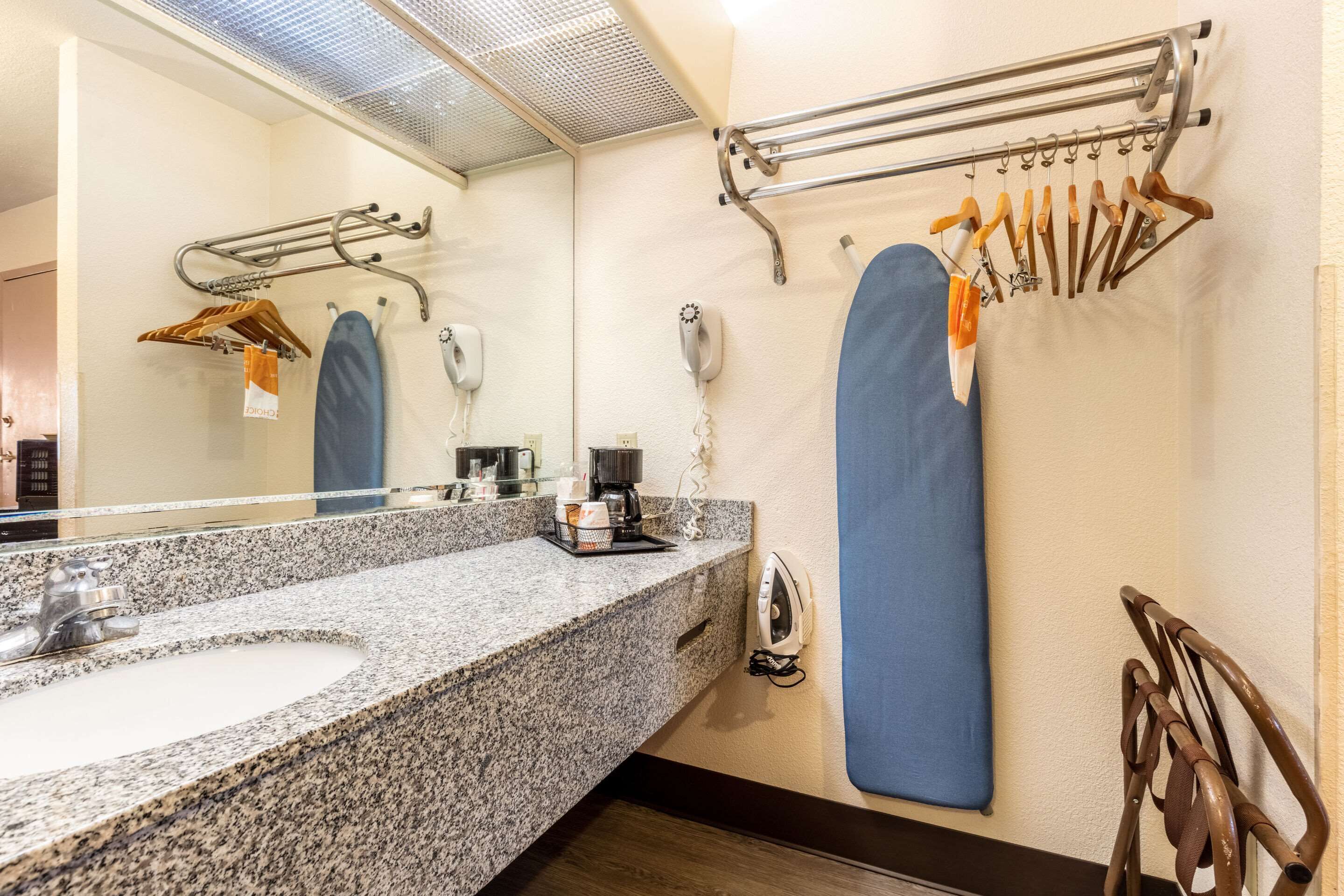 A bathroom with a granite sink, a mirror, a towel rack, a hairdryer, and a shower curtain.